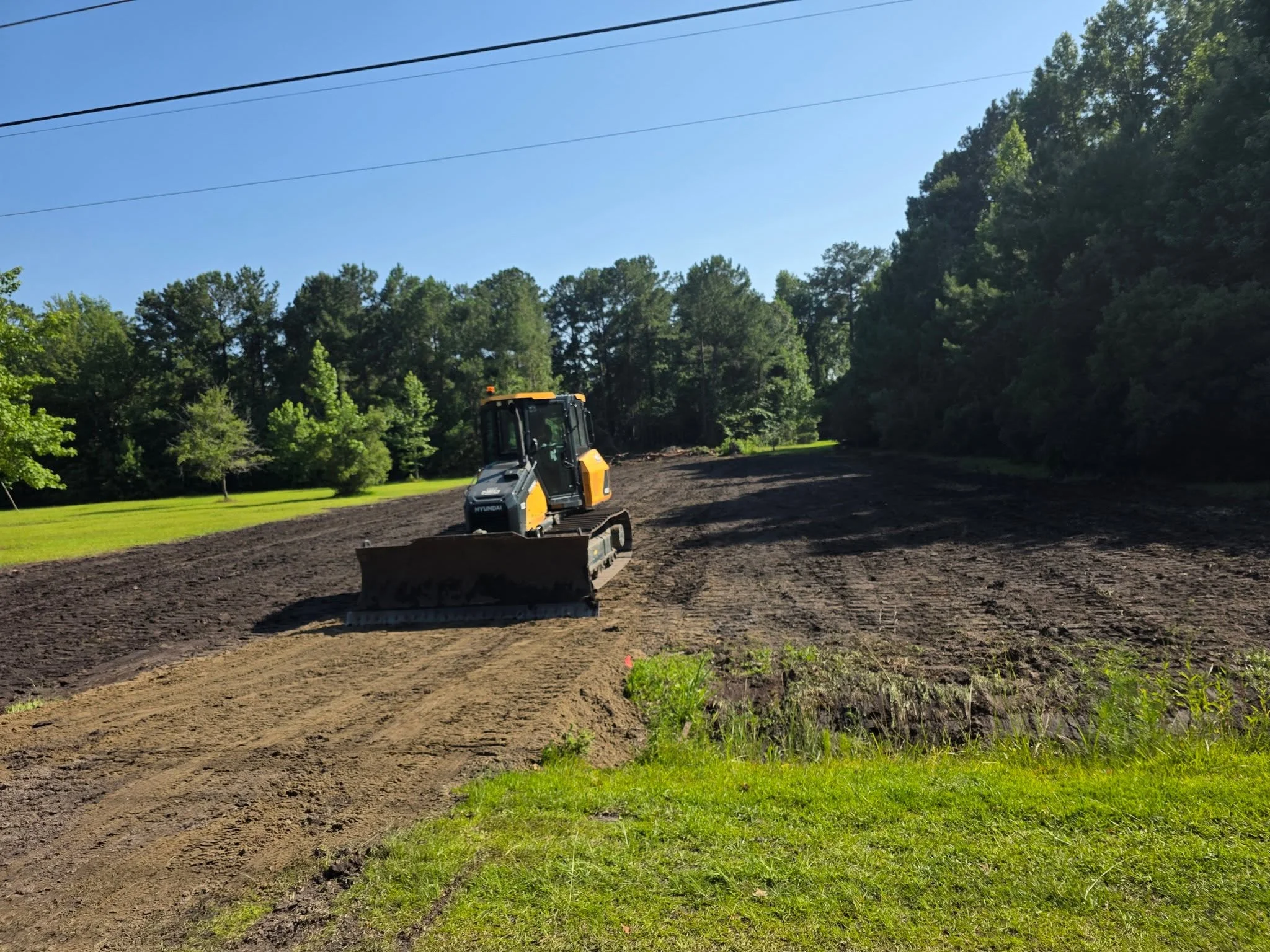 Skid steer loader grading and compacting soil on residential property
