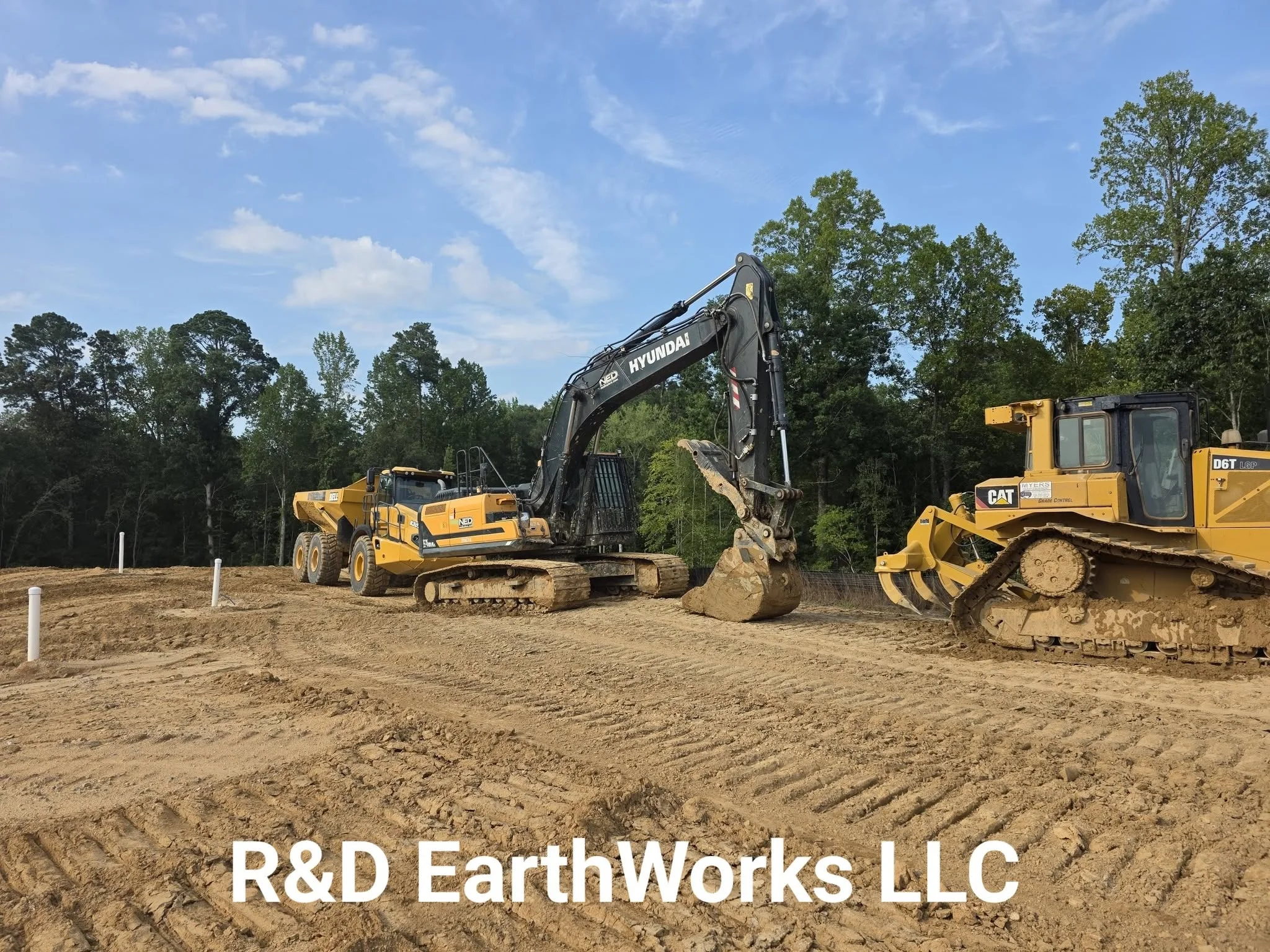 Hyundai excavator and CAT dozer performing site excavation and grading on cleared lot with earth material