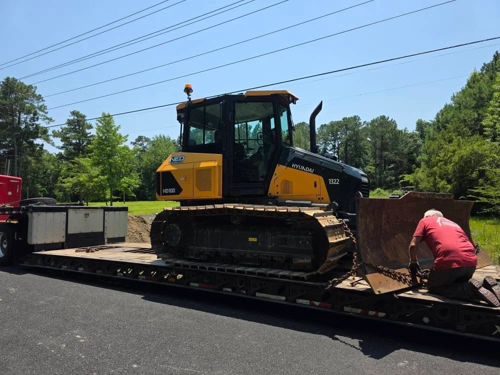 Hyundai HD100 dozer secured on flatbed trailer with chains during equipment delivery